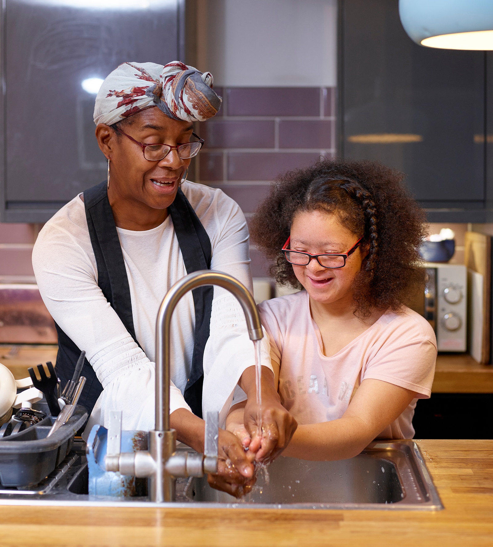 Woman helping developmentally delayed individual wash their hands